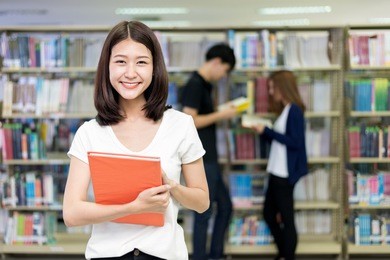group of asian students studying together in library at university. university students
