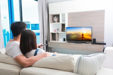 happy family watches television while sitting on the sofa.