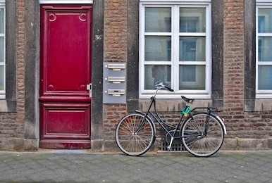 brugge, belgium. old town building with red door. parked bicycle.