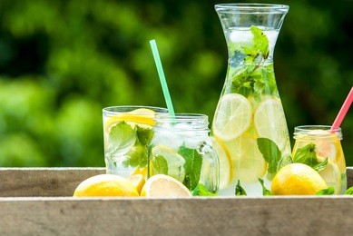 fresh homemade lemonade in pincher and jar of green blurred background