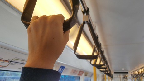 hand holding a handle in a mass rapid transit (mrt) train with blurred background.
