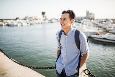 portrait of smiling asian man  near sea boats in the old european city
