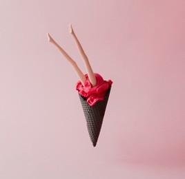 doll legs in red ice cream with black cone on pink pastel background. creative summer concept.