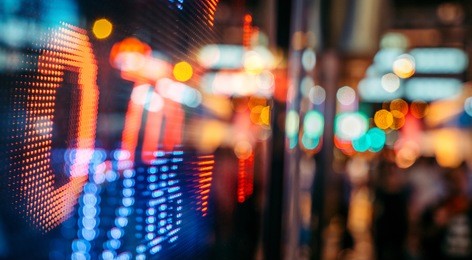 display of stock market quotes with city scene reflect on glass