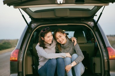 two happy asia woman friends enjoying road trip in hatchback car,flare light