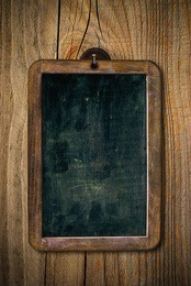 dirty and scratched wooden school slate over a wood wall, vertical image