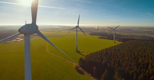 wind turbines and agricultural fields on a summer day - energy production with clean and renewable energy - aerial shot, analog image style