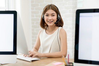 beautiful asian business woman wearing microphone headset working in the office as a telemarketing customer service agent, call center job concept