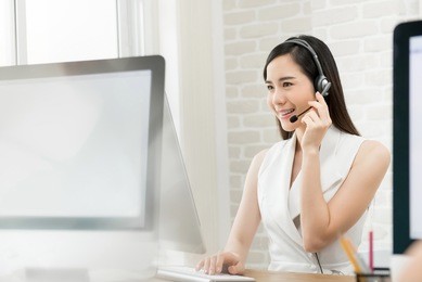 beautiful asian business woman wearing microphone headset working in the office as a telemarketing customer service agent, call center job concept