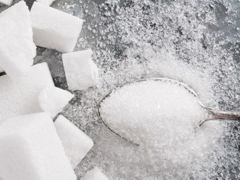 sugar background. sugar cubes and granulated sugar in spoon. white sugar on gray galvanized iron background. top view or flat lay. copy space.