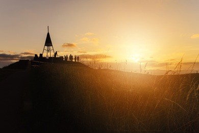 the beautiful sunset and the silhouette of tourist on the summit of mt.eden an iconic volcano in auckland, new zealand.