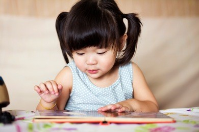 charming and lovely asian kid concentrated on reading book