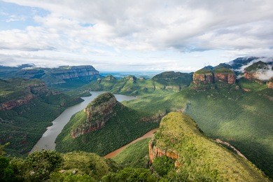 blyde river canyon on a cloudy day with a rainbow coming through 