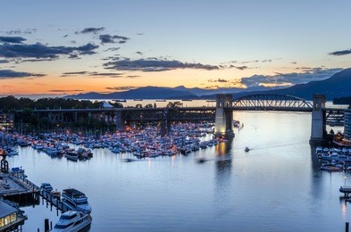 burrard street bridge and granville island marina at dusk, english bay and north vancouver are visible in background. vancouver, bc, canada