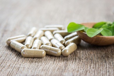 herbal capsules with moringa leaf on wooden table for healthy eating supplement 