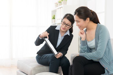 pretty elegant business manager woman using mobile digital tablet pad showing insurance scheme and explaining plan for buyer.