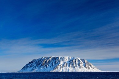 rocky island with snow. white snowy mountain, blue glacier svalbard, norway. beautiful landscape from land of ice. cold blue water and nature.