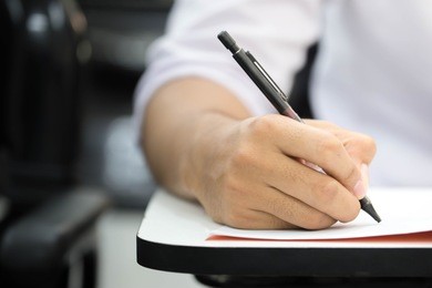 soft focus.university or high school student holding pencil.sitting on row chair writing final exam in examination room or study in classroom.education concept