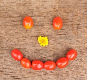 cherry tomatoes with smiling face on wooden background.tomatoes smile face with yellow nose on wooden background.