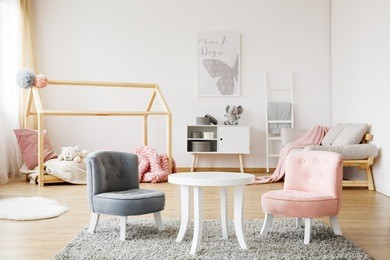 grey and pink small cute chairs standing on soft carpet in cozy baby room