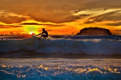 thai boy sunset surfing - this is photograph taken during quiksilver 2010 thailand surfing tournament. tournament took place 22-26 of november 2010 on kata beach phuket thailand.