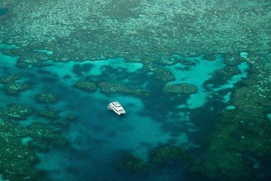 lonely catamaran in the great barrier reef as seen on the outer reef away from the whitsunday islands and airlie beach.