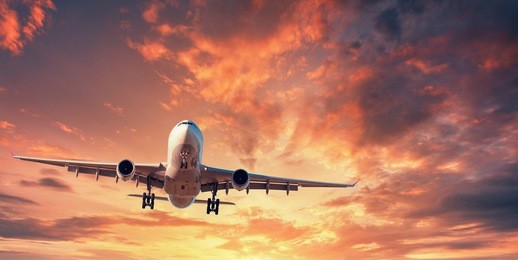landing airplane. landscape with white passenger airplane is flying in the orange sky with clouds at colorful sunset. travel background. passenger airliner. business trip. commercial aircraft. concept