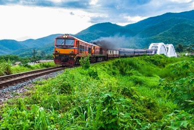 old train running through white concrete bridge