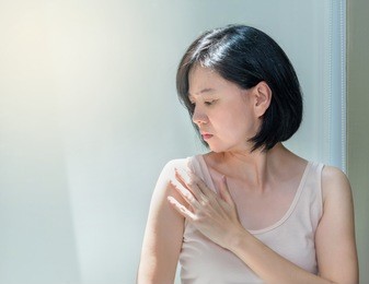 portrait of beautiful asian woman with healthy skin and short black hair worried about her body skin. middle aged woman checking her shoulder under sun light, skin care or beauty concept, copy space.
