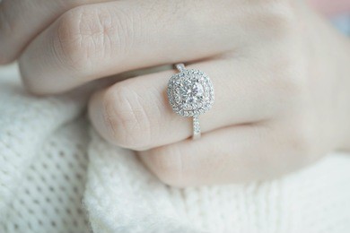 close up diamond ring on woman's finger before wedding with white scarf background.(soft and selective focus)