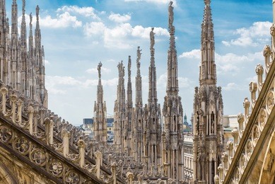 the beautiful roof of milan cathedral (duomo di milano) in milan, italy. architectural detail background. milan cathedral is the main travel attraction of milan. duomo in the sunlight on blue sky.