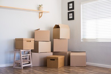 stack of cardboard boxes in an empty room. pile of carton boxes on the floor in an empty apartment. stack of moving boxes in new house.