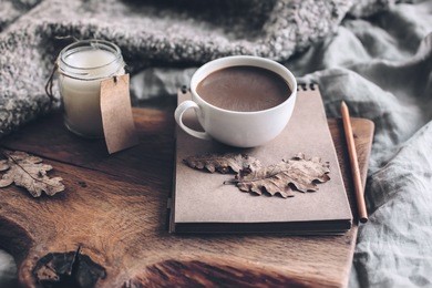 cup of coffee and candle on rustic wooden serving tray with blanket. spending autumn weekend in the cozy bed.