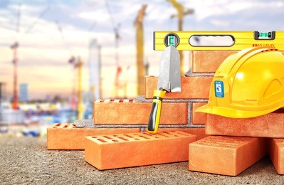 construction concept. part of brick wall in construction process with construction tools on a blurred construction site background. 3d illustration