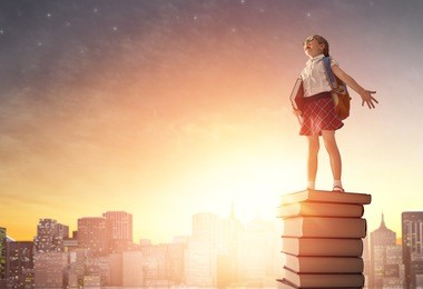back to school! happy cute industrious child standing on books on background of sunset urban landscape. concept of education and reading. the development of the imagination.
