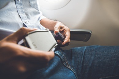 male passenger fastening seat belt while sitting on the airplane for safe flight