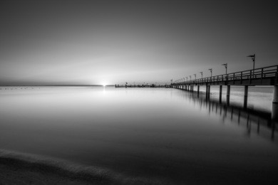 amazing sunrise on the pier at the seaside. mechelinki, poland. black and white photo