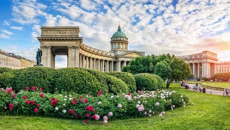 kazan cathedral in st. petersburg under a blue sky with clouds and beautiful red and white peonies in front of him