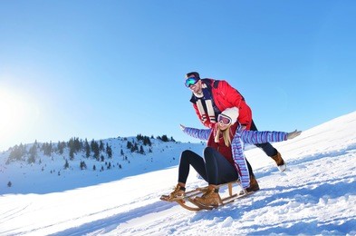 young couple sledding and enjoying on sunny winter day