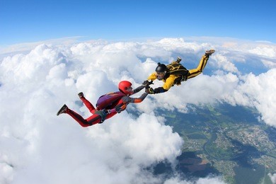two skydivers are falling in the background of the white clouds.