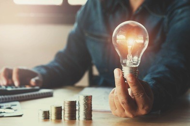 business accounting with saving money with hand holding lightbulb concept financial background