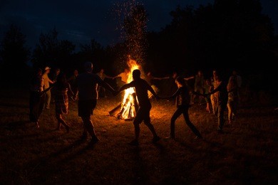 people dance around the campfire. people dance around the fire at night.