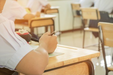 asian girl students in uniform taking examination in classroom educational, view of college people having exams and test in seat rows at exam class room at high school, education concept
