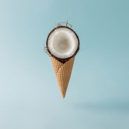 coconut with ice cream cone on pastel blue background. foos creative concept.