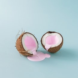 coconut cracked in half with pink milk pouring. minimalism. food creative concept.