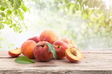 ripe peaches with leaves on a wooden board on a background of green leaves