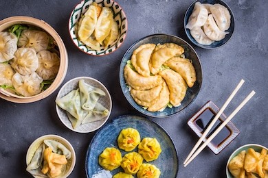 assorted dim sum appetizers on rustic background. set of chinese food for share. asian buffet. traditional chinese dim sum food. top view. different chinese dumplings and snacks on table