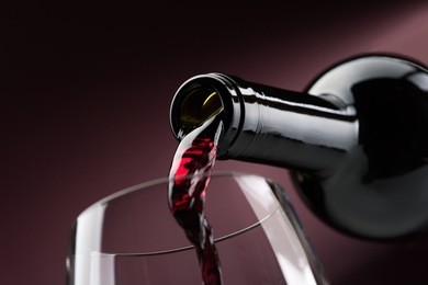 pouring red wine from a bottle into a wineglass: wine tasting and celebration