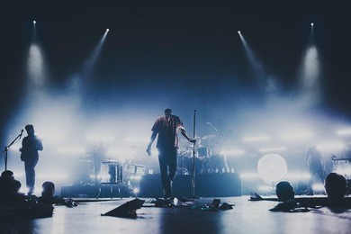 music band / group silhouette perform on a concert stage.  dark background, smoke, concert  spotlights, singer holds a microphone stand.