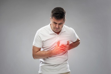 people, healthcare and problem concept - unhappy man suffering from heart ache over gray background